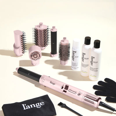 The Frizz-Free Routine Value Set, featuring the blush TurboStyle Styling & Drying System, Top Coat, Frizz Care Shampoo, and Frizz Care Conditioner on a beige background